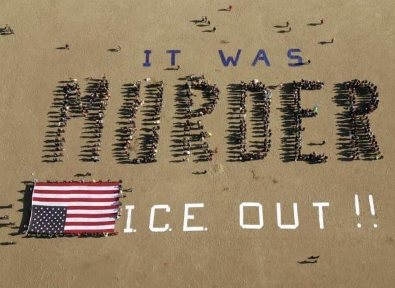 Aerial photograph of hundreds of people lined up on a beach spelling the word murder with their bodies. Above them, they have used objects to write the words "it was," and below them they have used more objects to write "ICE Out!!". There is also another group holding a very large American flag upside down.