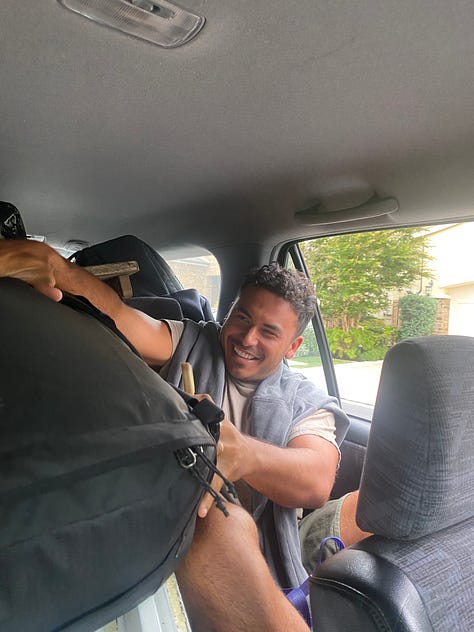 small voyaging canoe up on the sandy beaches on a gray chilly day. Our friend Kalani stuffing and trying to manage many bags and tools stuffed into a car seat. An uncle towing our boat with a side tie and a small engine boat used for paddling races.