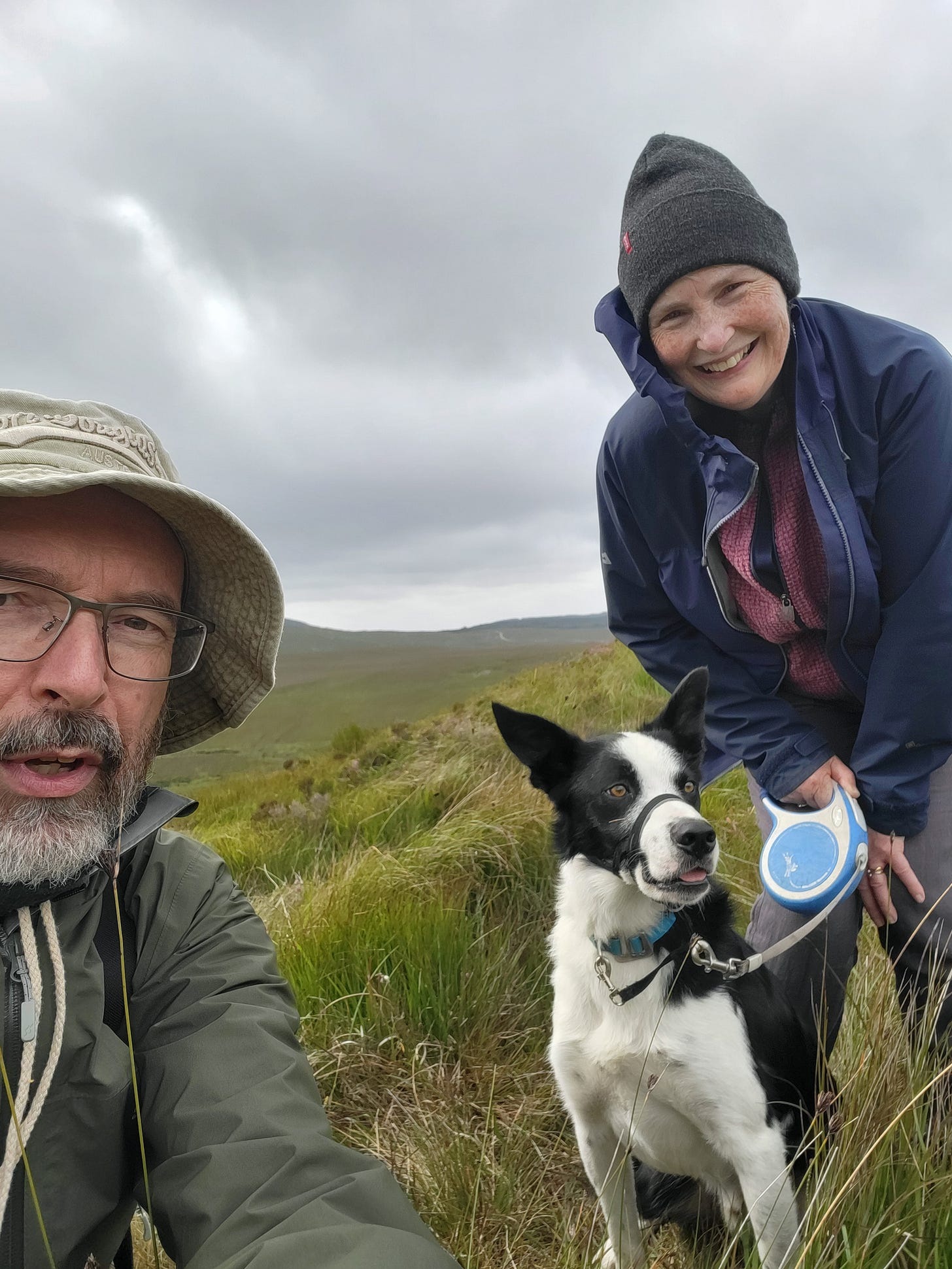 Man and woman with black and white smooth-haired collie in open countryside in Ireland