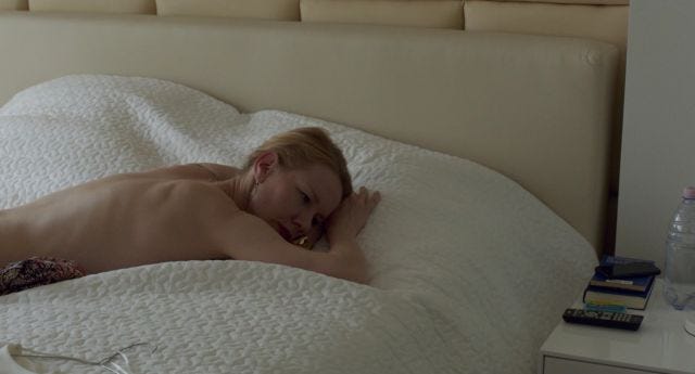 Woman lies naked face down on top of a duvet Woman lies naked face down on top of a duvet