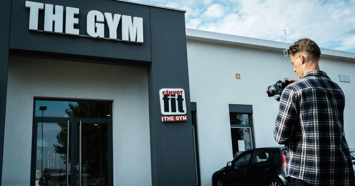 man stood outside a gym with a camera in hand