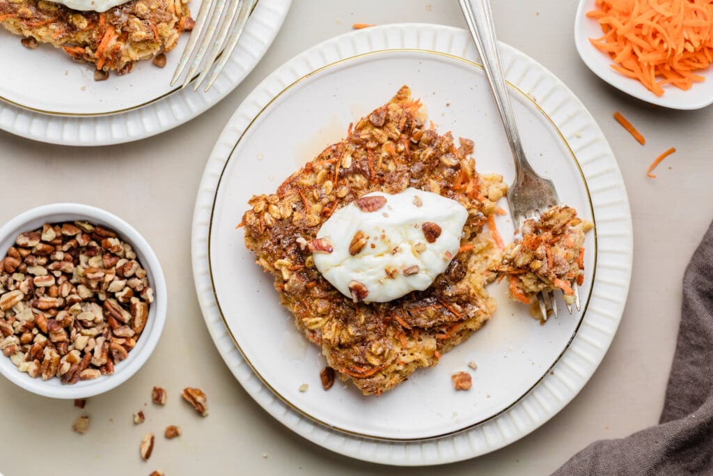Close-up of carrot cake baked oatmeal topped with a dollop of frosting and chopped pecans.