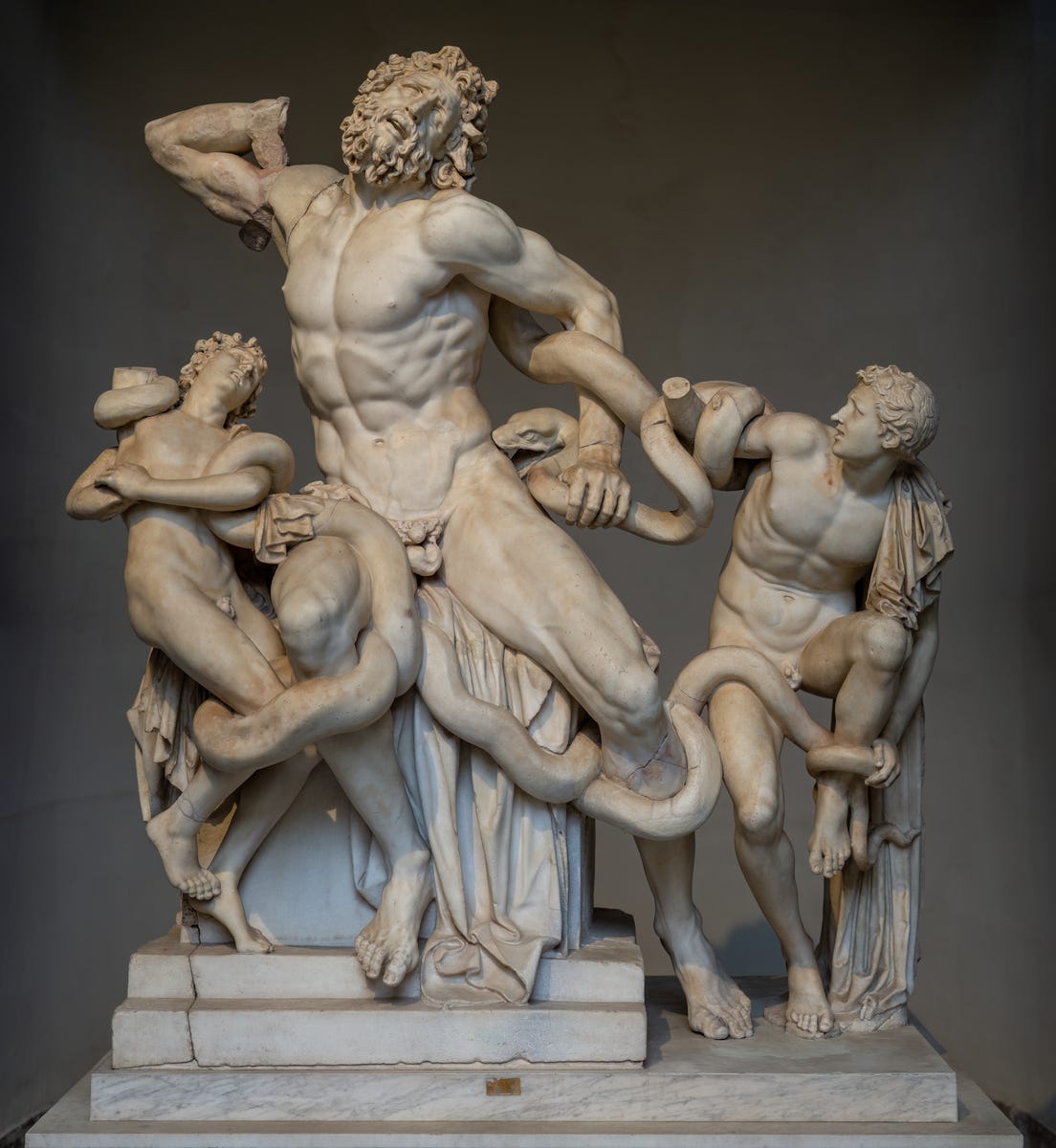A marble sculpture depicting the dramatic scene of Laocoön and his two sons being attacked by serpents. The central figure, Laocoön, is a muscular, bearded man in a contorted pose, struggling against a snake coiling around his body. His face expresses intense pain and anguish. On either side, his two sons are also entangled by the serpents, each displaying fear and desperation. The sculpture is detailed and dynamic, with intricate depictions of human anatomy and the sinuous movement of the snakes, emphasizing the tension and suffering in the scene. The artwork rests on a pedestal with a neutral background. Photo by Wilfredo Rafael Rodriguez Hernandez - Own work, CC0, via <a href='https://commons.wikimedia.org/w/index.php?curid=145566250'>Wikimedia</a> A marble sculpture depicting the dramatic scene of Laocoön and his two sons being attacked by serpents. The central figure, Laocoön, is a muscular, bearded man in a contorted pose, struggling against a snake coiling around his body. His face expresses intense pain and anguish. On either side, his two sons are also entangled by the serpents, each displaying fear and desperation. The sculpture is detailed and dynamic, with intricate depictions of human anatomy and the sinuous movement of the snakes, emphasizing the tension and suffering in the scene. The artwork rests on a pedestal with a neutral background. Photo by Wilfredo Rafael Rodriguez Hernandez - Own work, CC0, via <a href='https://commons.wikimedia.org/w/index.php?curid=145566250'>Wikimedia</a>