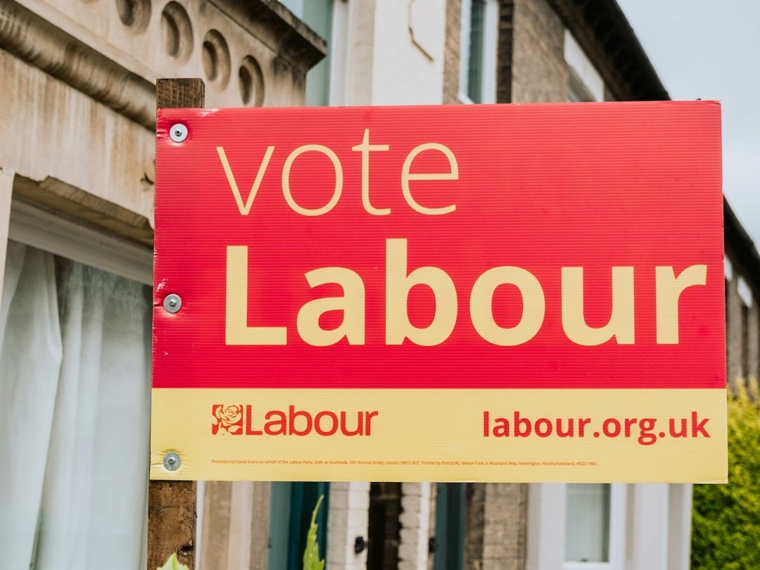 a red and yellow vote labour sign in front of a house