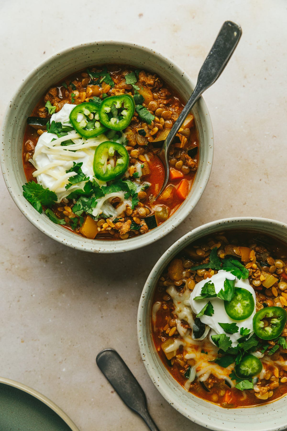 Turkey lentil chili in two serving bowls with toppings.
