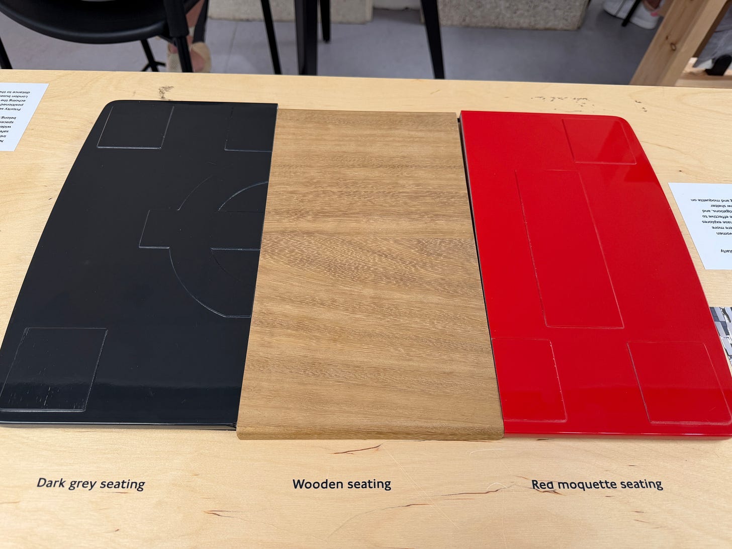 Photo showing samples of seat materials, dark grey, wooden and red. Photo showing samples of seat materials, dark grey, wooden and red.