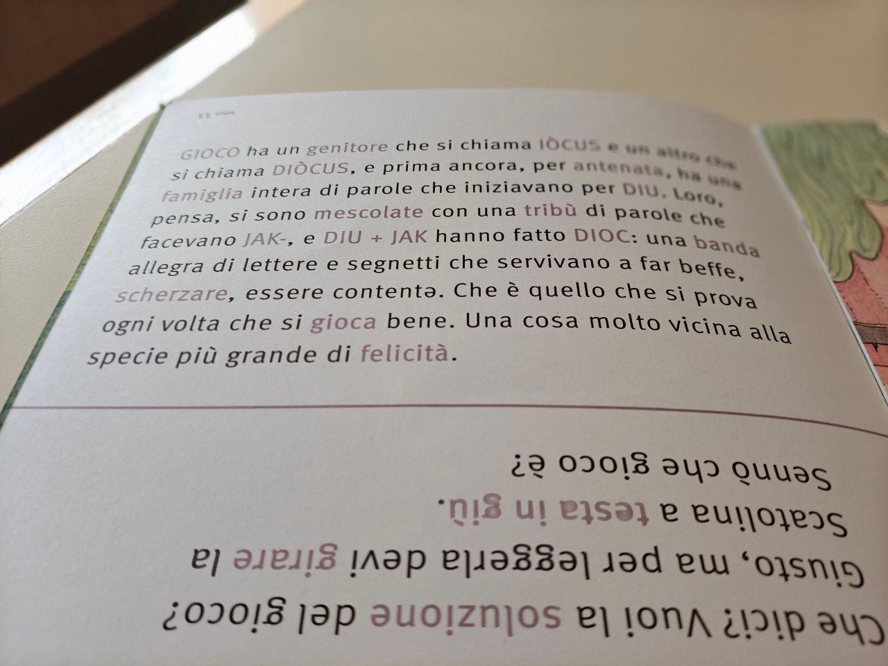 Una pagina della parola GIOCO delle Scatoline di effequ, con questa scritta: "GIOCO ha un genitore che si chiama IOCUS e un altro genitore che si chiama DIOCUS, e prima ancora, per antenata, ha una famiglia intera di parole che iniziavano per DIU. Loro, pensa, si sono mescolate con una tribù di parole che facevano JA-, E DIU + JAK hanno fatto DIOC: una banda allegra di lettere e segnetti che servivano a far beffe, scherzare, essere contente. Che è quello che si prova ogni volta che si gioca bene. Una cosa molto vicina alla specie più grande di felicità.". La pagina è appoggiata su un tavolo di legno bianco sporco e nell'angolino in alto a destra si intravede un pezzetto di muro in ombra.