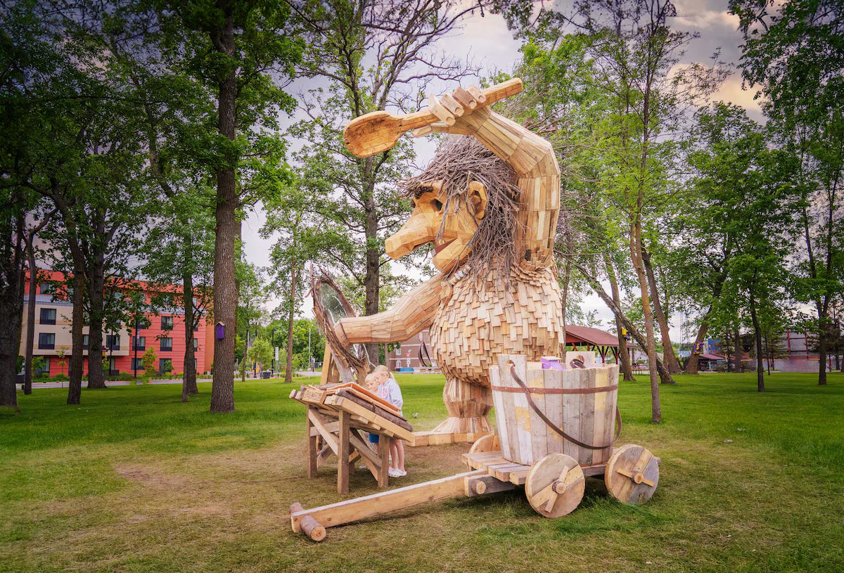 A wooden sculpture of a troll in a park

Description automatically generated