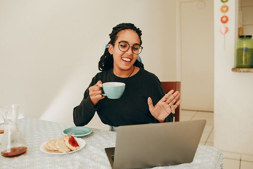 Staff member waving in a video conference meeting.