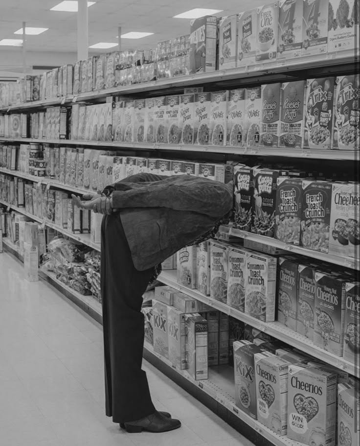 Señor en un supermercado metiendo la cabeza entre las cajas de cereales.