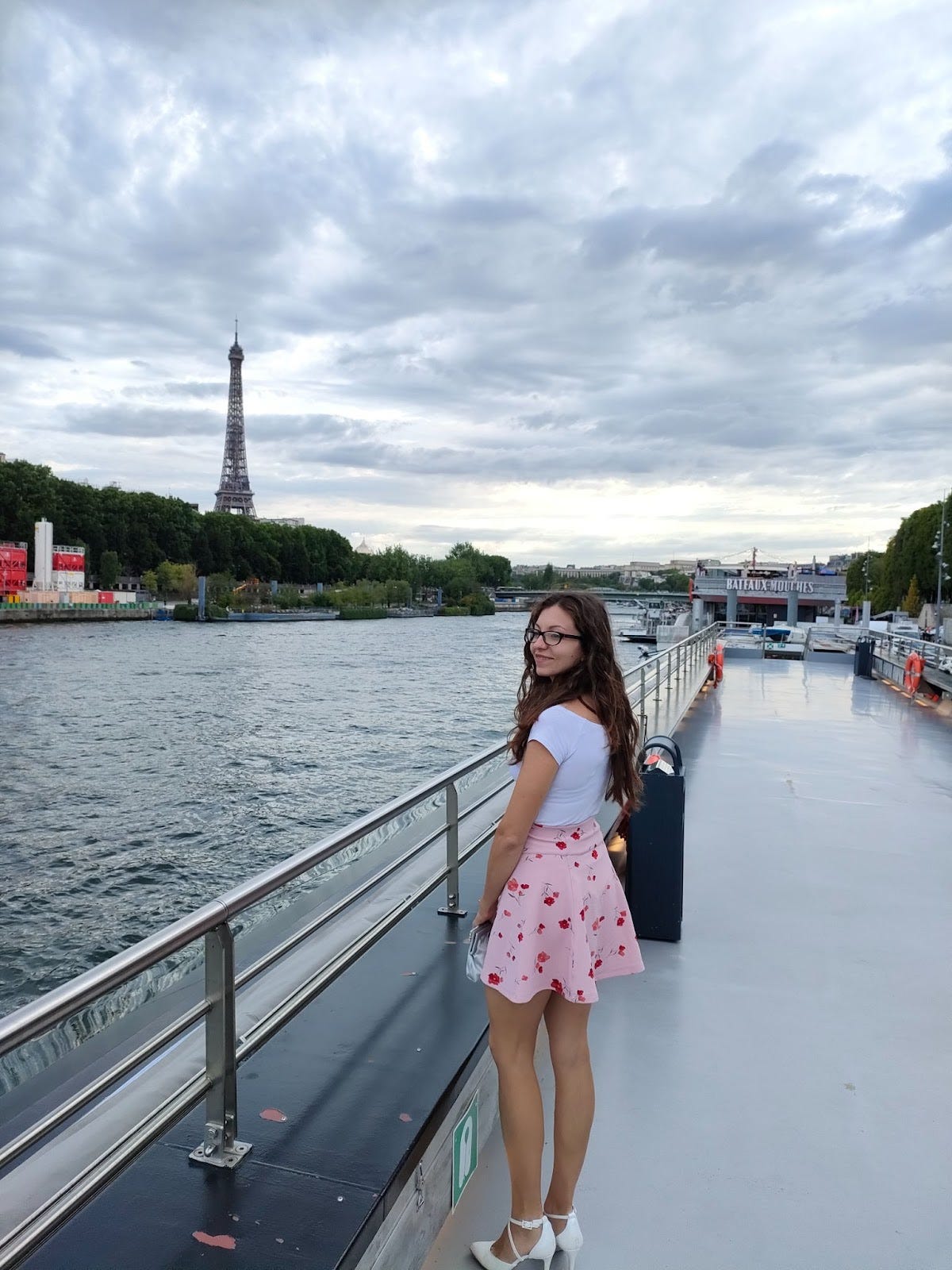Person smiling while looking out from the deck of a boat on the Seine during a river cruise in Paris.