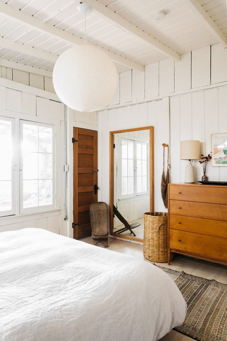 This may contain: a bedroom with white walls and wooden furniture