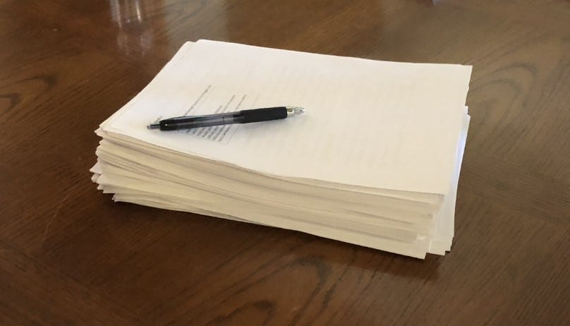 A thick manuscript topped with a pen A thick manuscript topped with a pen