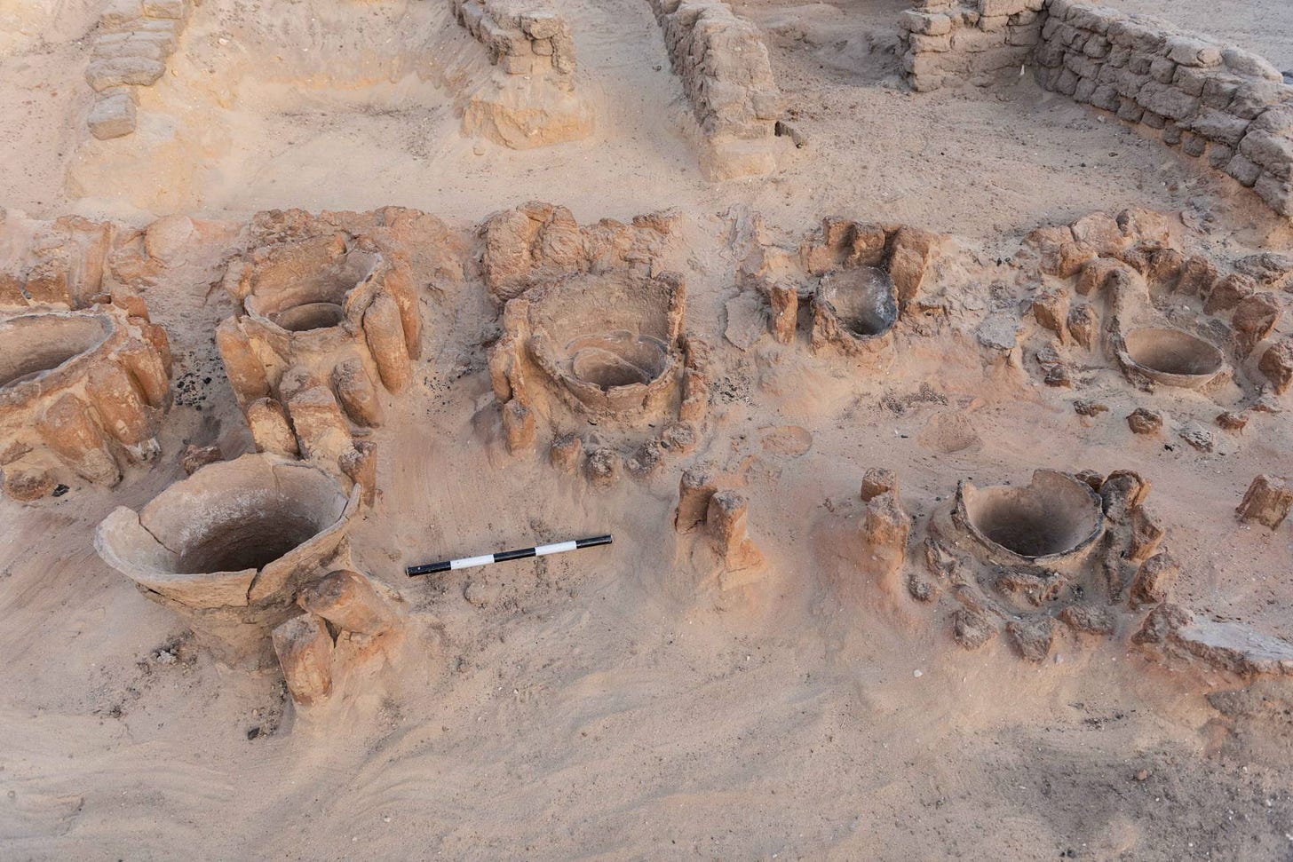 Openings of urns used to hold ingredients for brewing visible in the sand Openings of urns used to hold ingredients for brewing visible in the sand