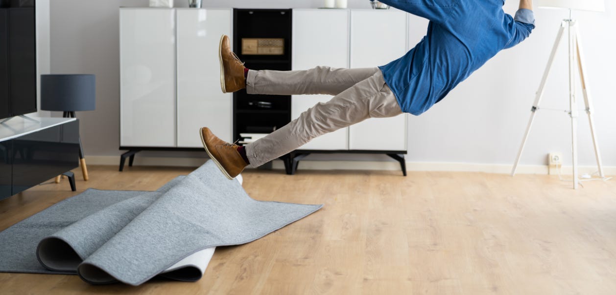 Rediculous image of a man slipping on a slippery rug. The rug is bunched up and he is flying backwards through the air