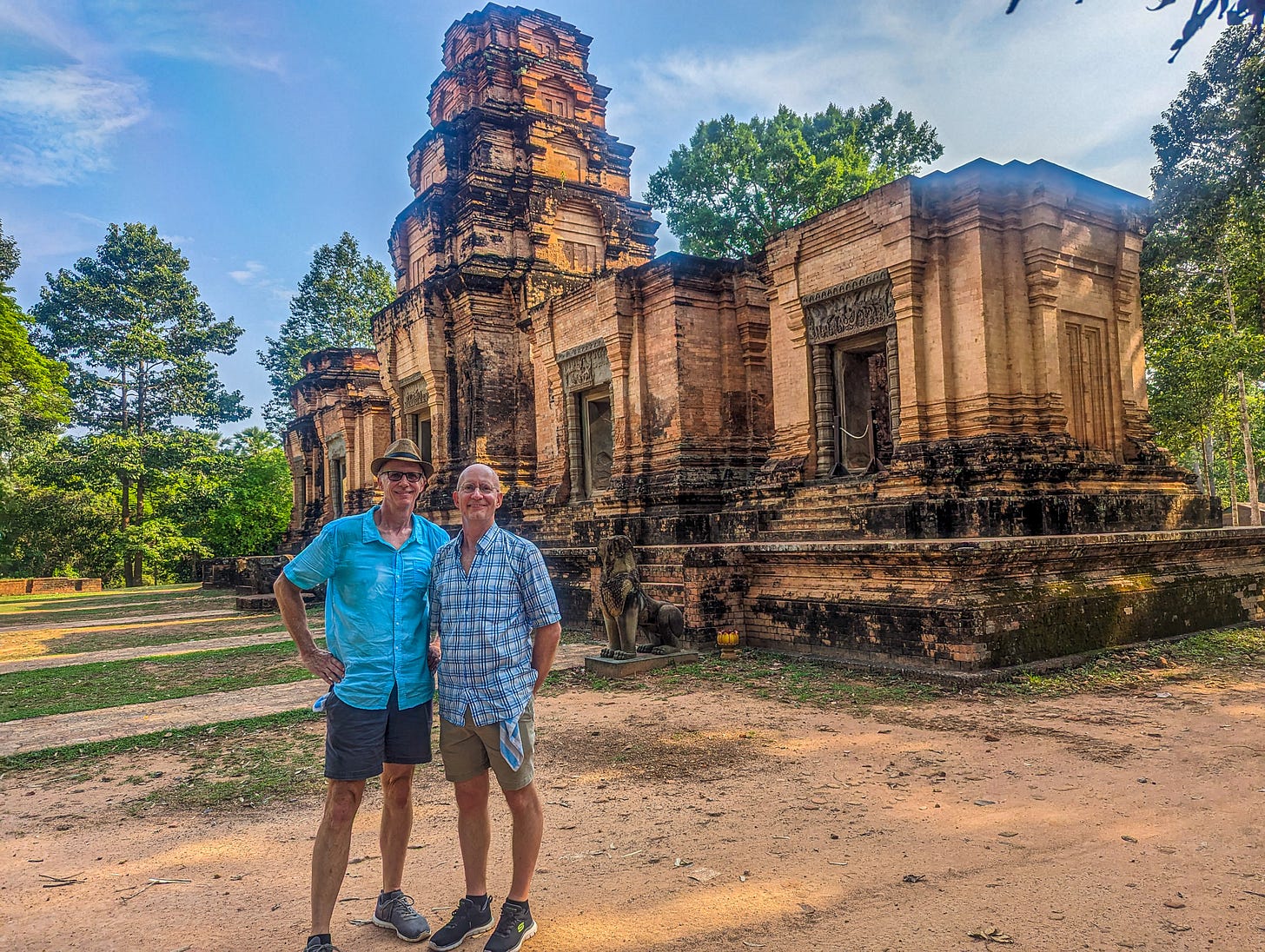 Brent and Michael standing in front of a red brick building, a multi-level tower rising up from the center. 