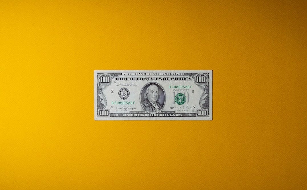 a one dollar bill sitting on top of a yellow wall