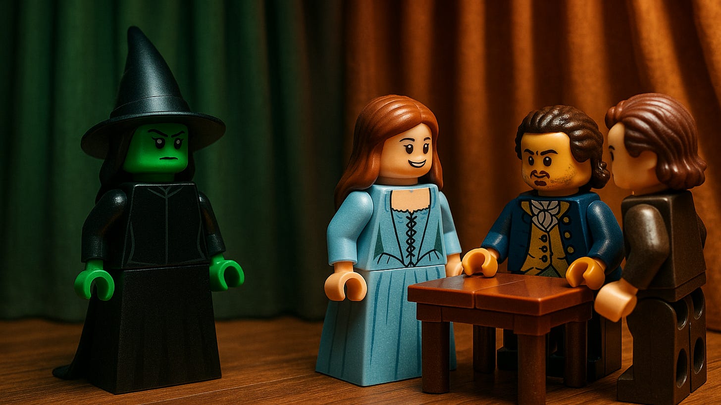Lego figures dressed as characters from the Wicked musical. There is an angry witch dressed in black with green skin looking towards a woman and two men dressed in old-fashioned clothes at a table.