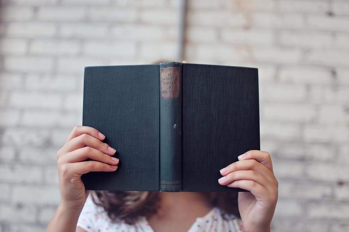 Selective Focus Photography of Woman Holding Book Selective Focus Photography of Woman Holding Book