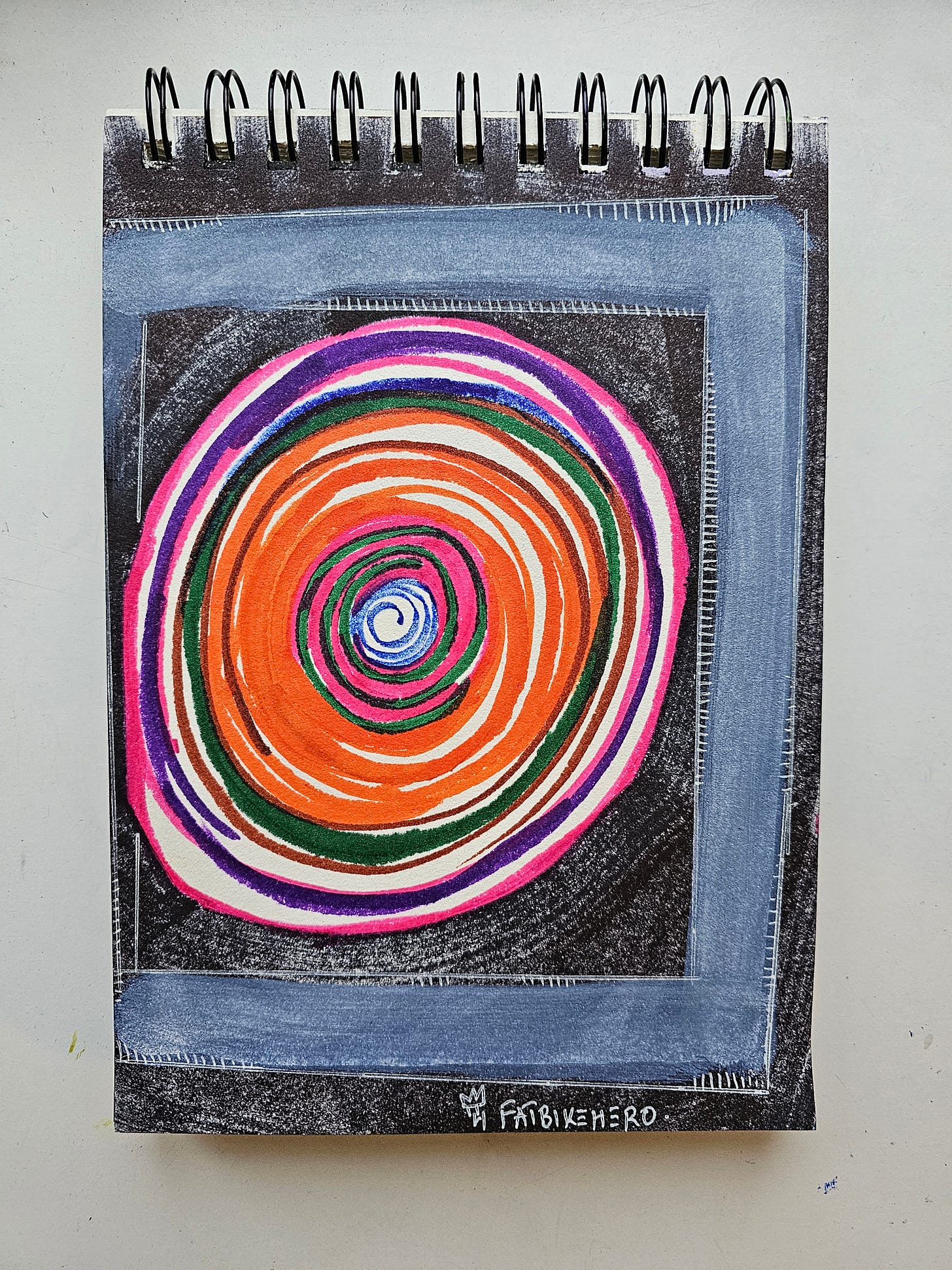 Alt Text: A sketchbook art piece by FatbikeHero featuring a vibrant, multi-colored spiral vortex in orange, pink, and green on a black background, enclosed by a thick grey hand-painted frame with white stitch marks. Alt Text: A sketchbook art piece by FatbikeHero featuring a vibrant, multi-colored spiral vortex in orange, pink, and green on a black background, enclosed by a thick grey hand-painted frame with white stitch marks.