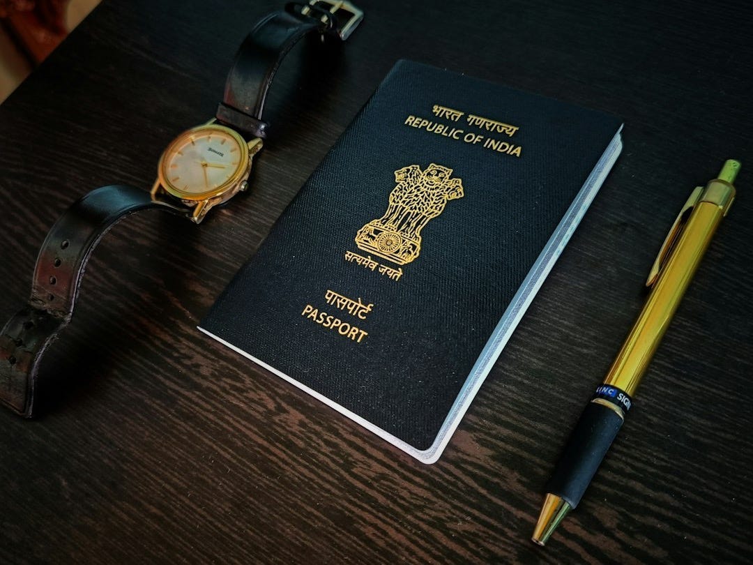 a passport, watch and pen on a table