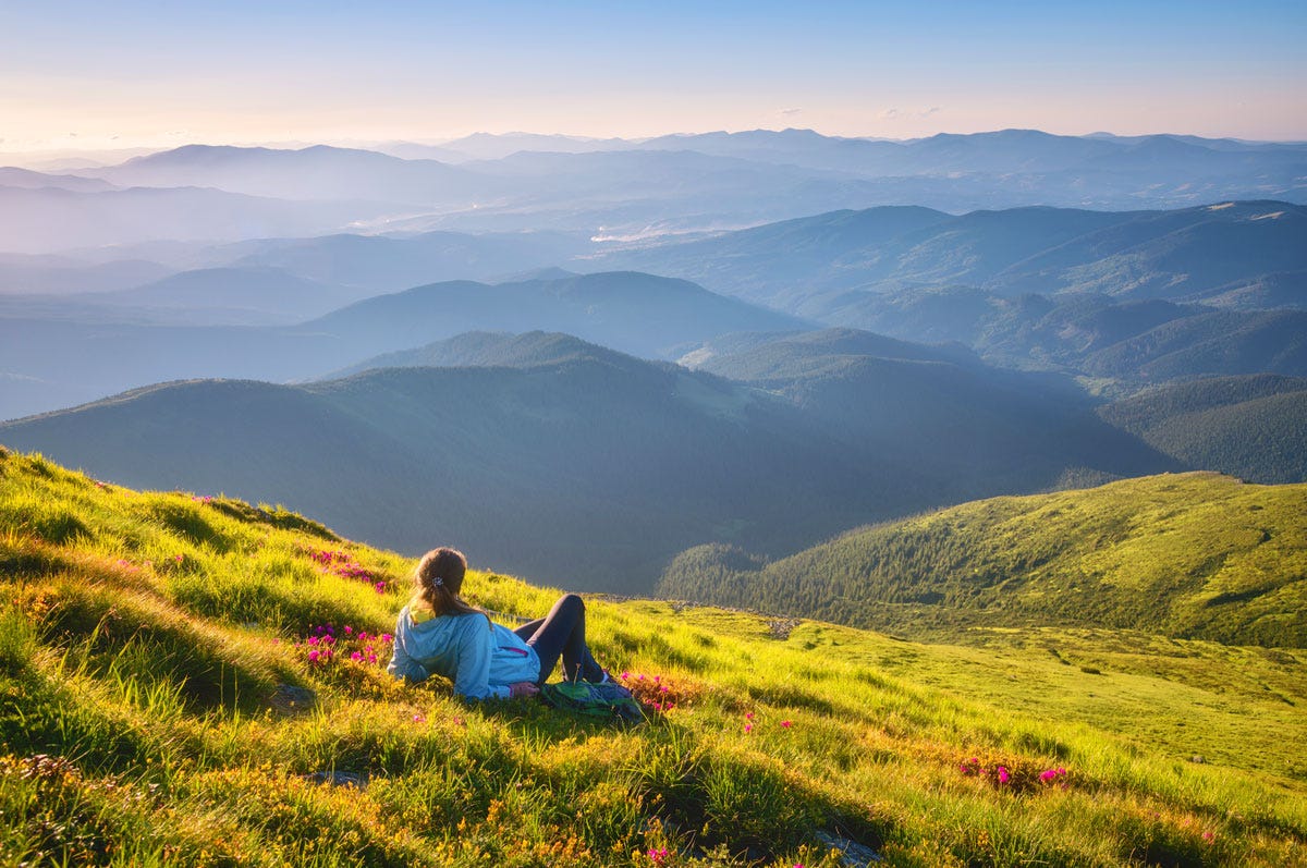 Person Lying in Field Enjoying Majestic Nature and Mountains Person Lying in Field Enjoying Majestic Nature and Mountains