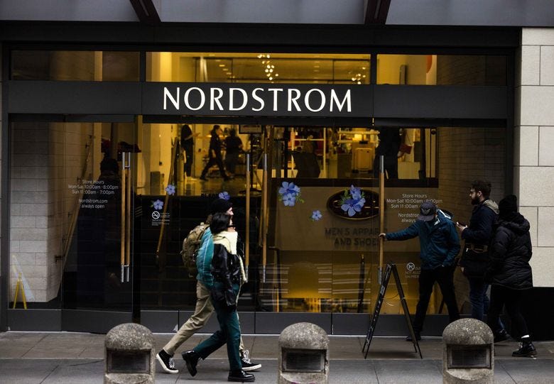 Pedestrians walk past the Nordstrom flagship store in downtown Seattle. The flagship store, in a building that also houses Nordstrom’s headquarters, remains a destination for Seattle-area residents and visitors alike. (Daniel Kim / The Seattle Times)