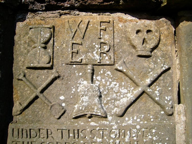 A stone carved with six symbols, including a skull and two bones crossed in an x.