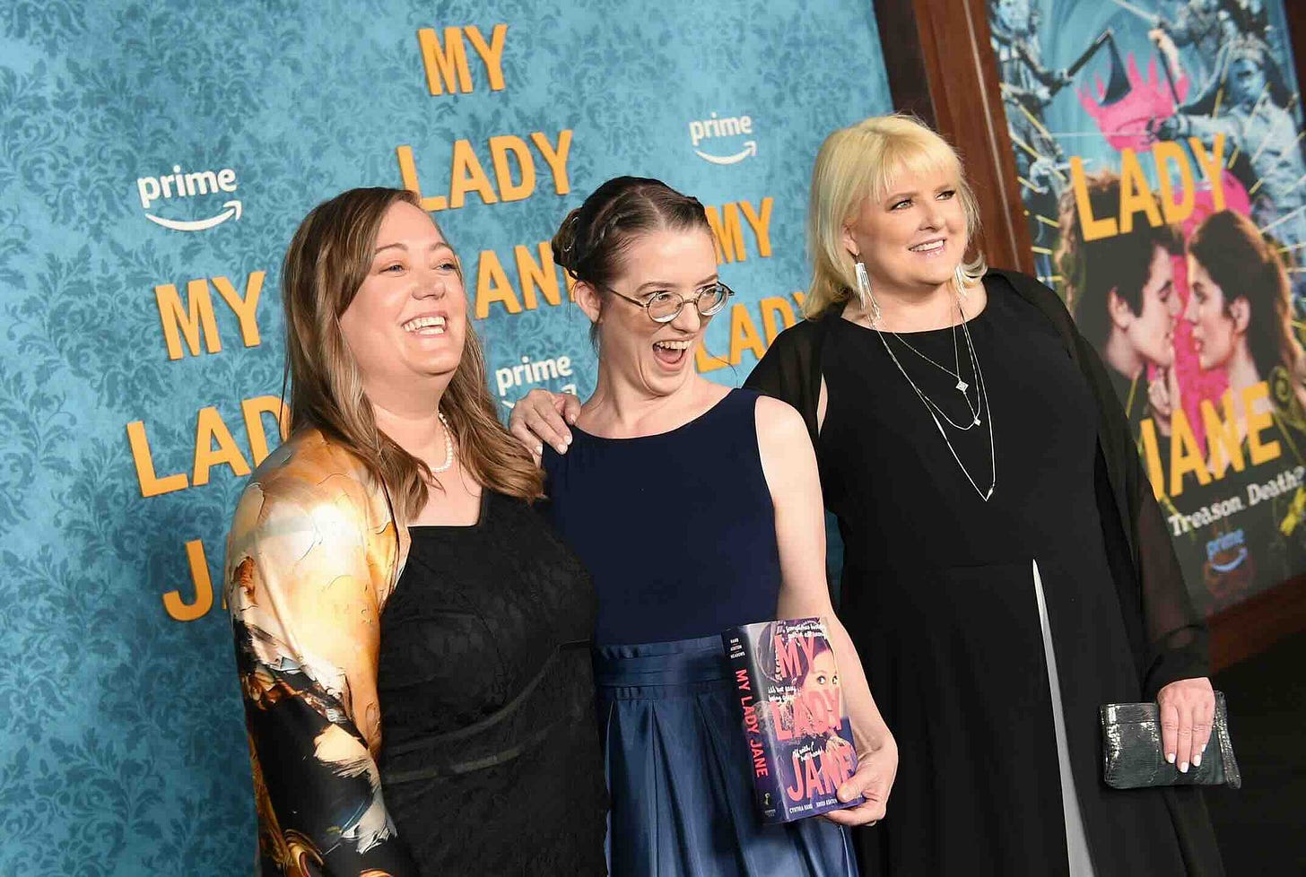 Janies on the red carpet. Everyone is grinning. The book is there too.