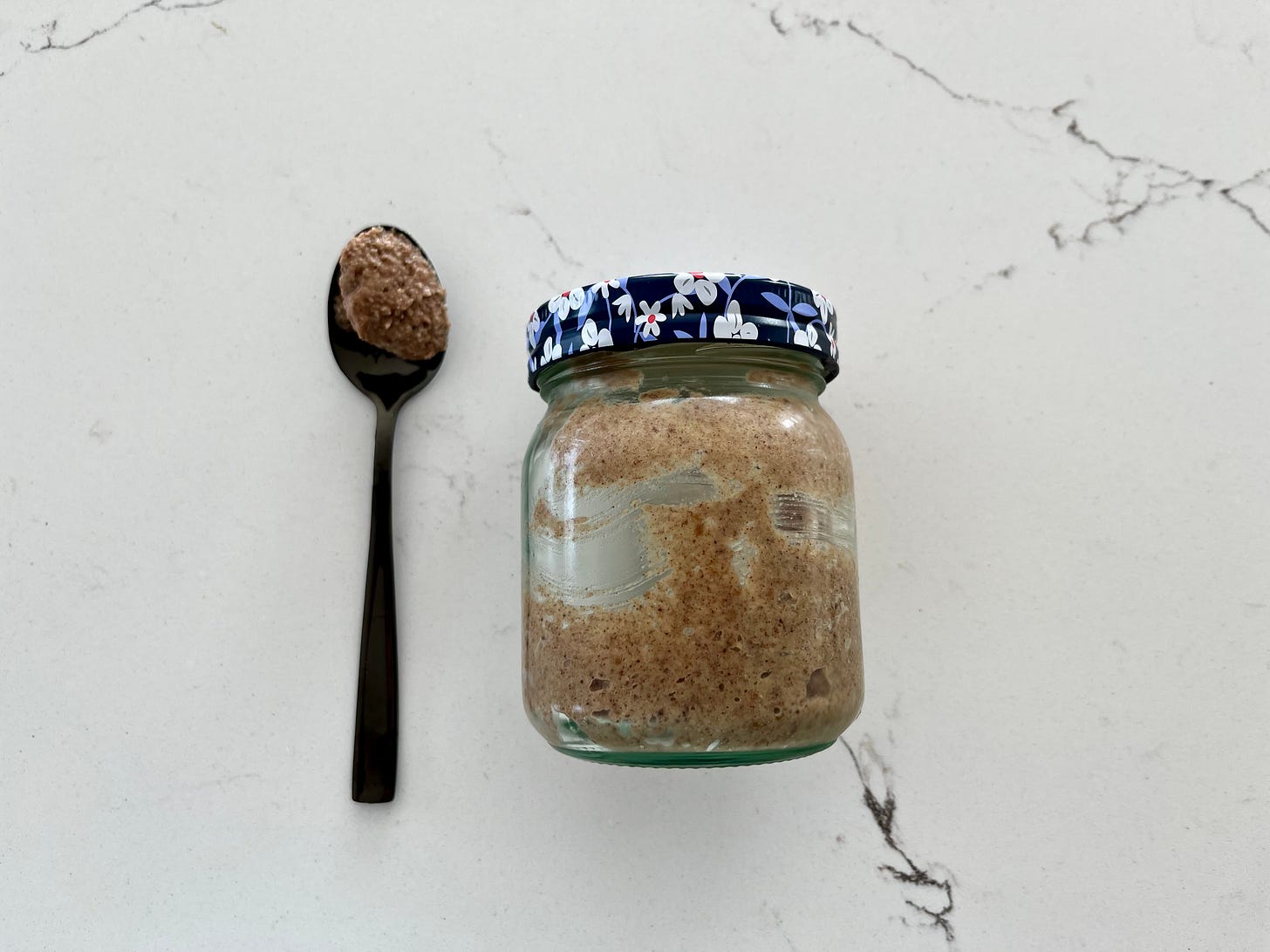 A spoonful of date paste, next to a jar of the same contents. A spoonful of date paste, next to a jar of the same contents.