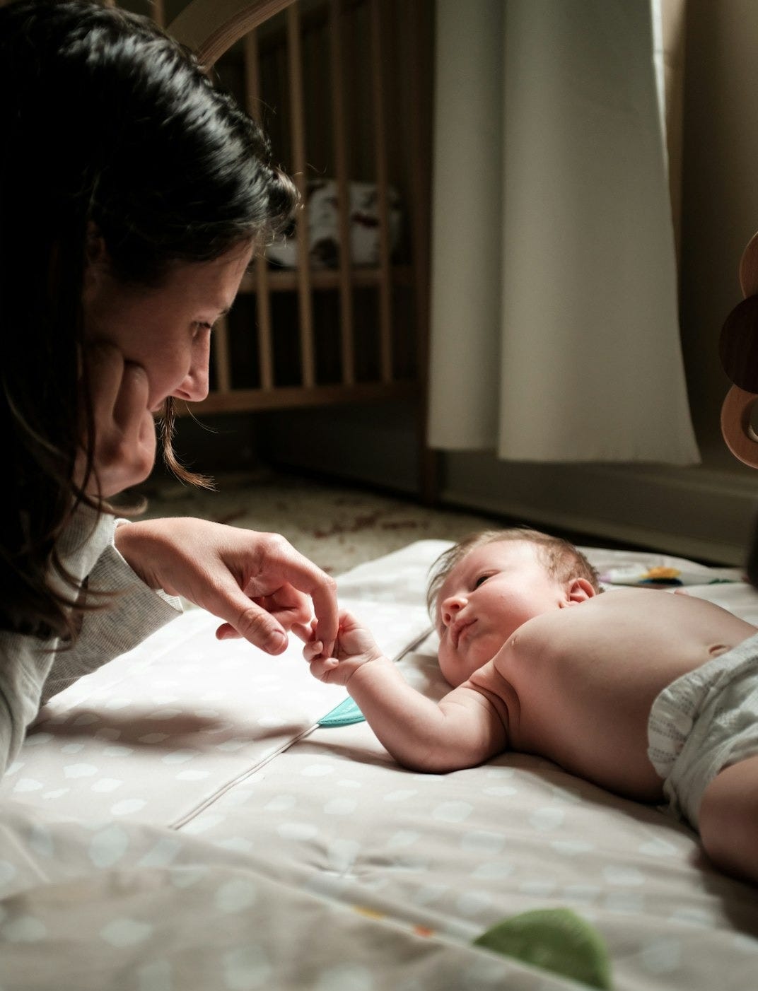a woman is touching a baby's hand on a bed