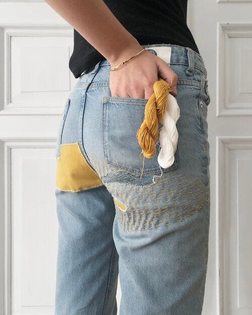 This may contain: a person wearing blue jeans with yellow and white yarn in their pocket This may contain: a person wearing blue jeans with yellow and white yarn in their pocket