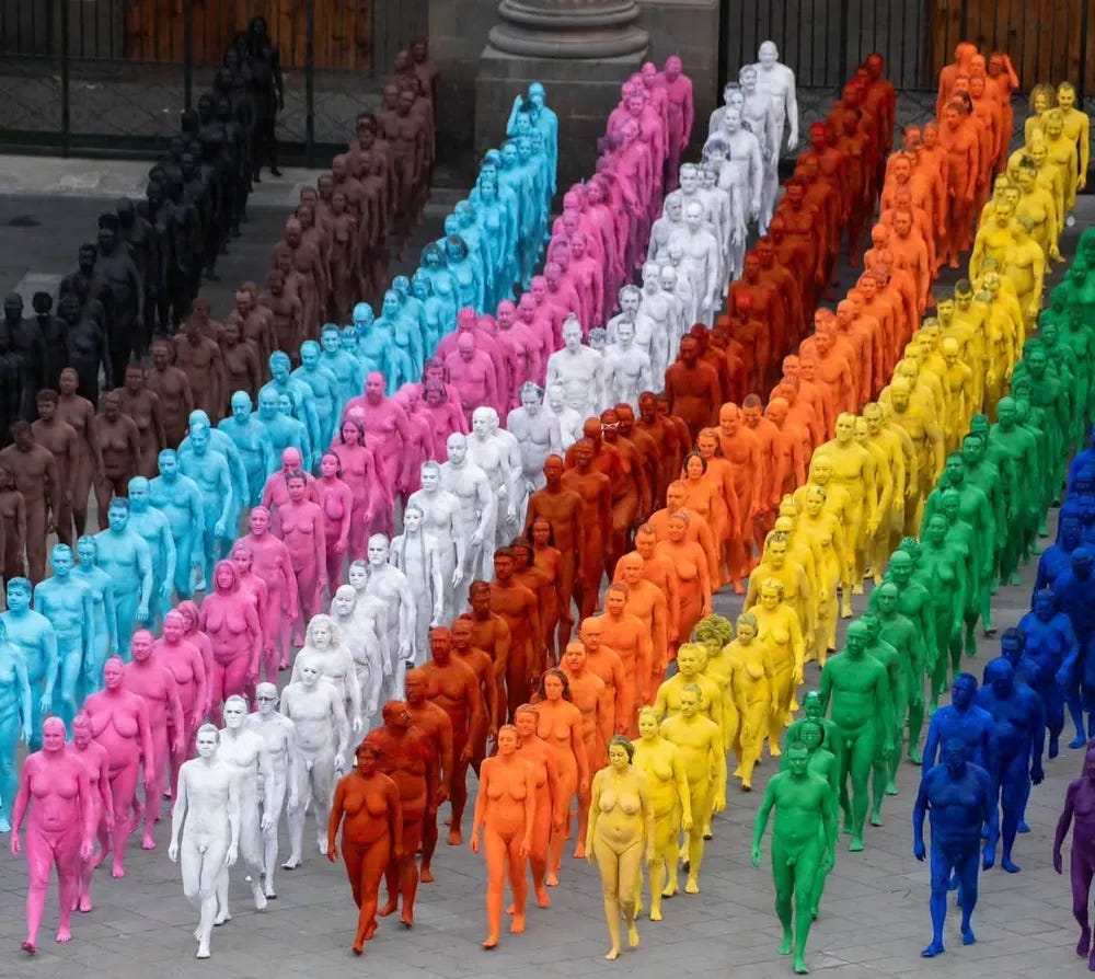 Hundreds of nude participants, each painted a different color of the rainbow, walk in parallel lines across the square in front of the Cathedral of Santa Ana in Las Palmas de Gran Canaria during a Spencer Tunick installation supporting LGBTIQ+ inclusion. Hundreds of nude participants, each painted a different color of the rainbow, walk in parallel lines across the square in front of the Cathedral of Santa Ana in Las Palmas de Gran Canaria during a Spencer Tunick installation supporting LGBTIQ+ inclusion.