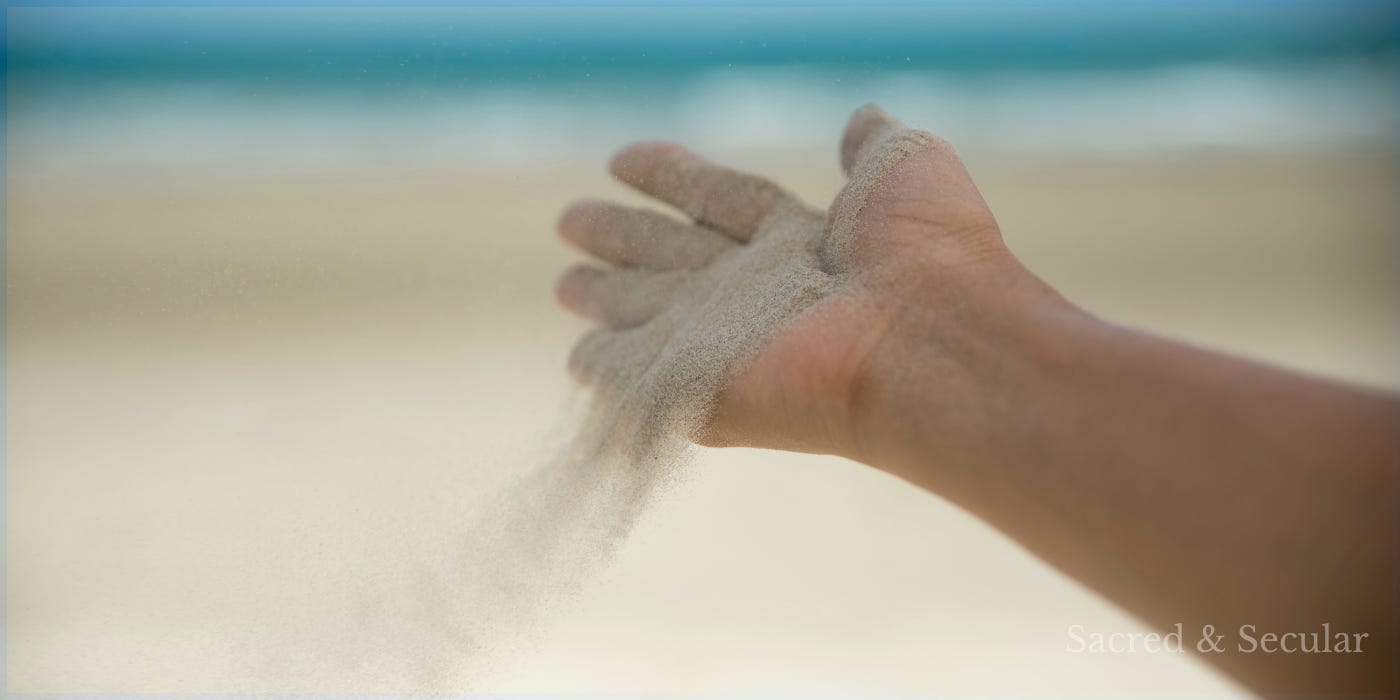 Hand releasing sand onto a beach Hand releasing sand onto a beach