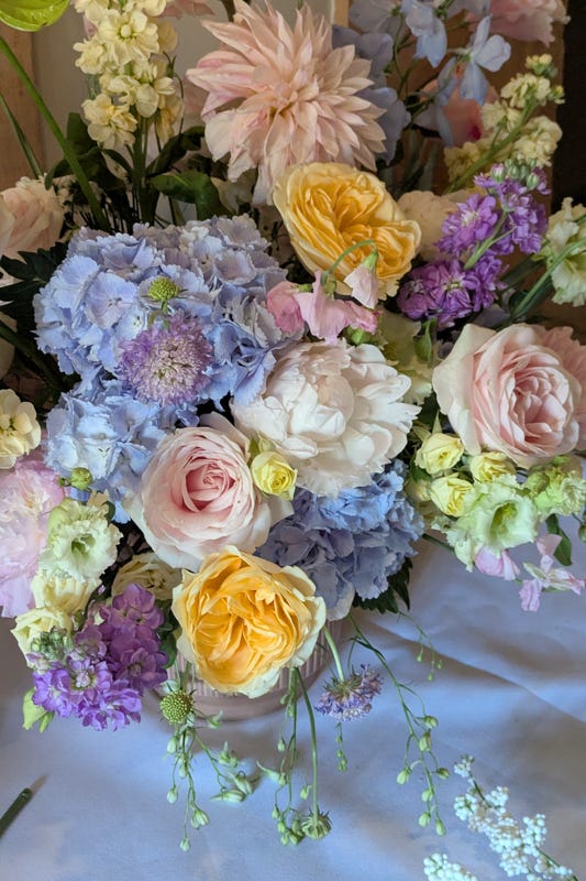 A colourful pastel wedding bouquet. A night view of a barn dressed up with festoon lights for an English countryside wedding.