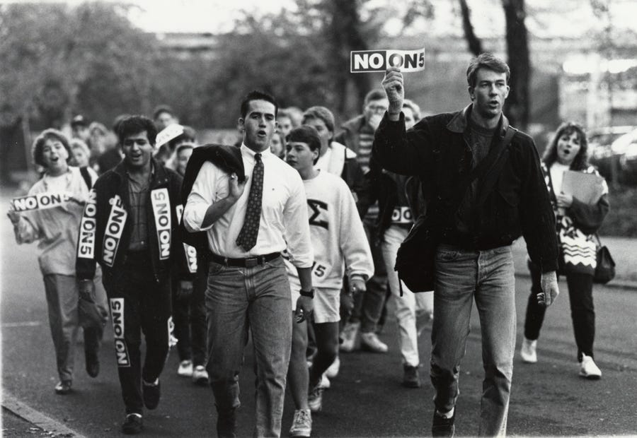 Young adults march carrying and wearing signs that read "NO ON 5" Young adults march carrying and wearing signs that read "NO ON 5"