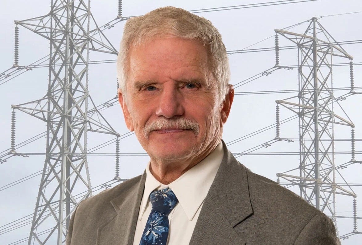 man in gray suit superimposed on photo of transmission lines