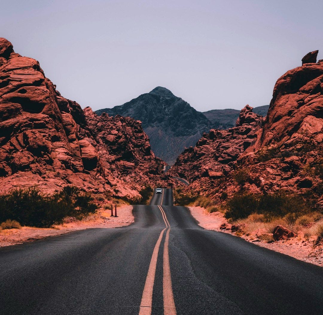 black concrete road surrounded by brown rocks black concrete road surrounded by brown rocks