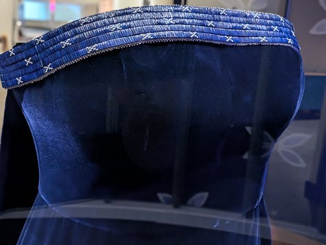 Midnight-blue velvet gown and black corseted dress with porcupine-quill neckline by Gucci and Joe Big Mountain of Ironhorse Quillwork. Worn by Lily Gladstone to the Oscars when she was nominated for Best Actress for Killers of the Flower Moon.