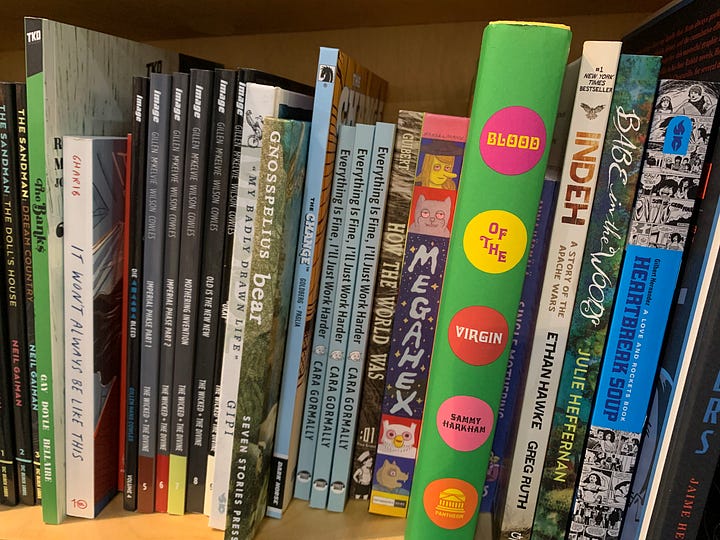 The author with their mouth agape in wonder and delight at their book in the wild in a bookstore; their book on a shelf