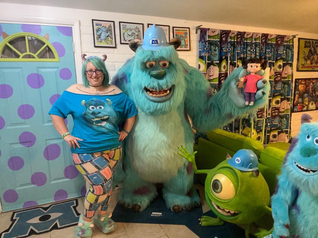 A woman stands in a room full of Monsters, Inc. memorabilia with a large Sulley statue.