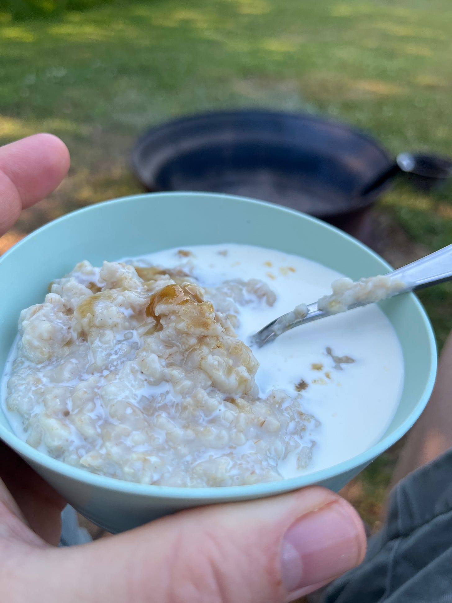 A small bowl of oatmeal with a bit of cream and brown sugar.