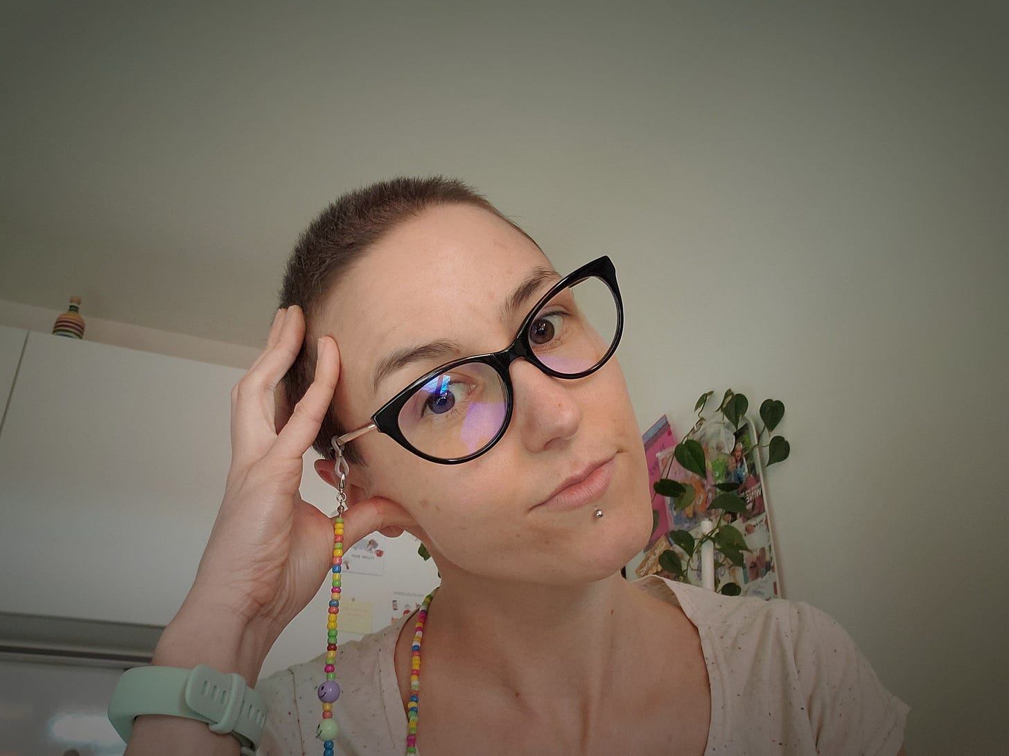 The photograph shows the author, a white woman, with her new buzz cut as she is looking into the camera, wearing glasses.