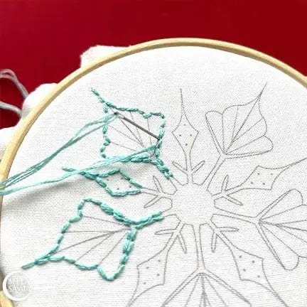 needle filling in light blue thread in center part of snowflake