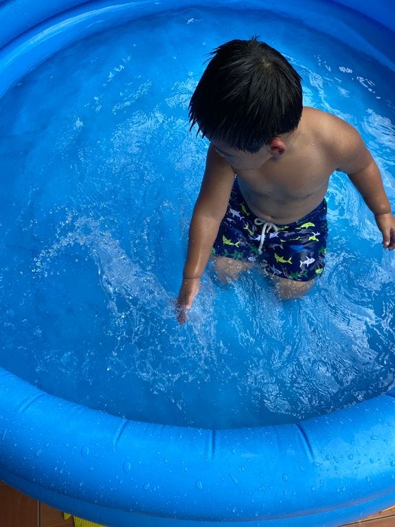 Little boy loving the water in an inflatable kiddie pool Little boy loving the water in an inflatable kiddie pool
