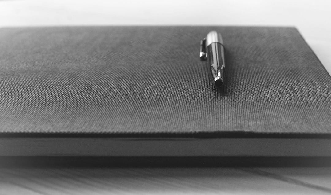 gray click pen on black book gray click pen on black book