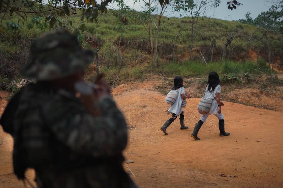 Dos niños del pueblo indígena Wiwa caminan frente a un combatiente de las Autodefensas Conquistadoras, en una vereda de la Sierra Nevada de Santa Marta.