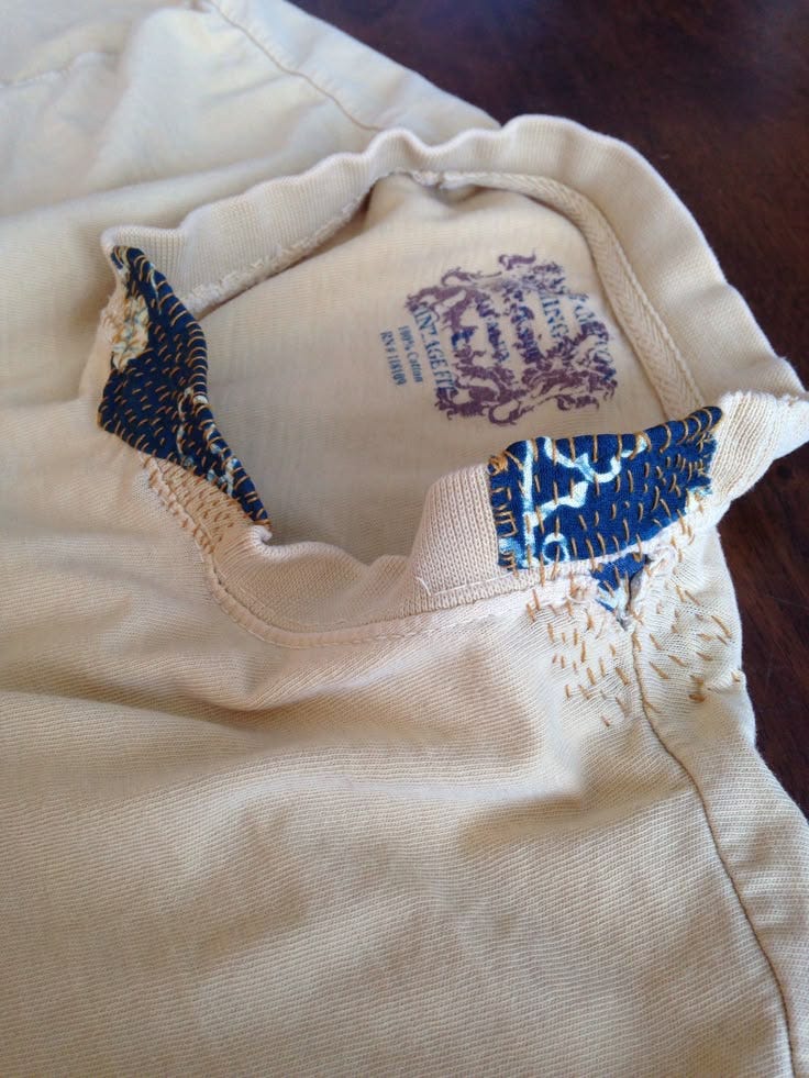 This may contain: the bottom half of a white t - shirt with blue and purple designs on it