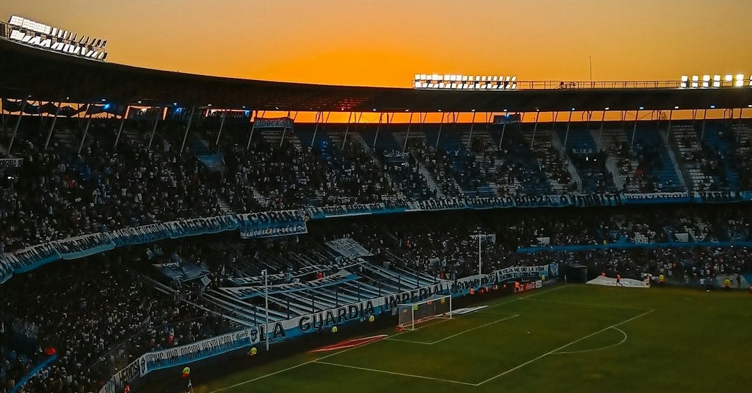 A stadium filled with lots of people watching a soccer game A stadium filled with lots of people watching a soccer game