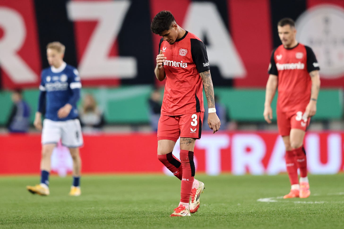 Piero Hincapie walks with his head down dejected after Leverkusen defeat.